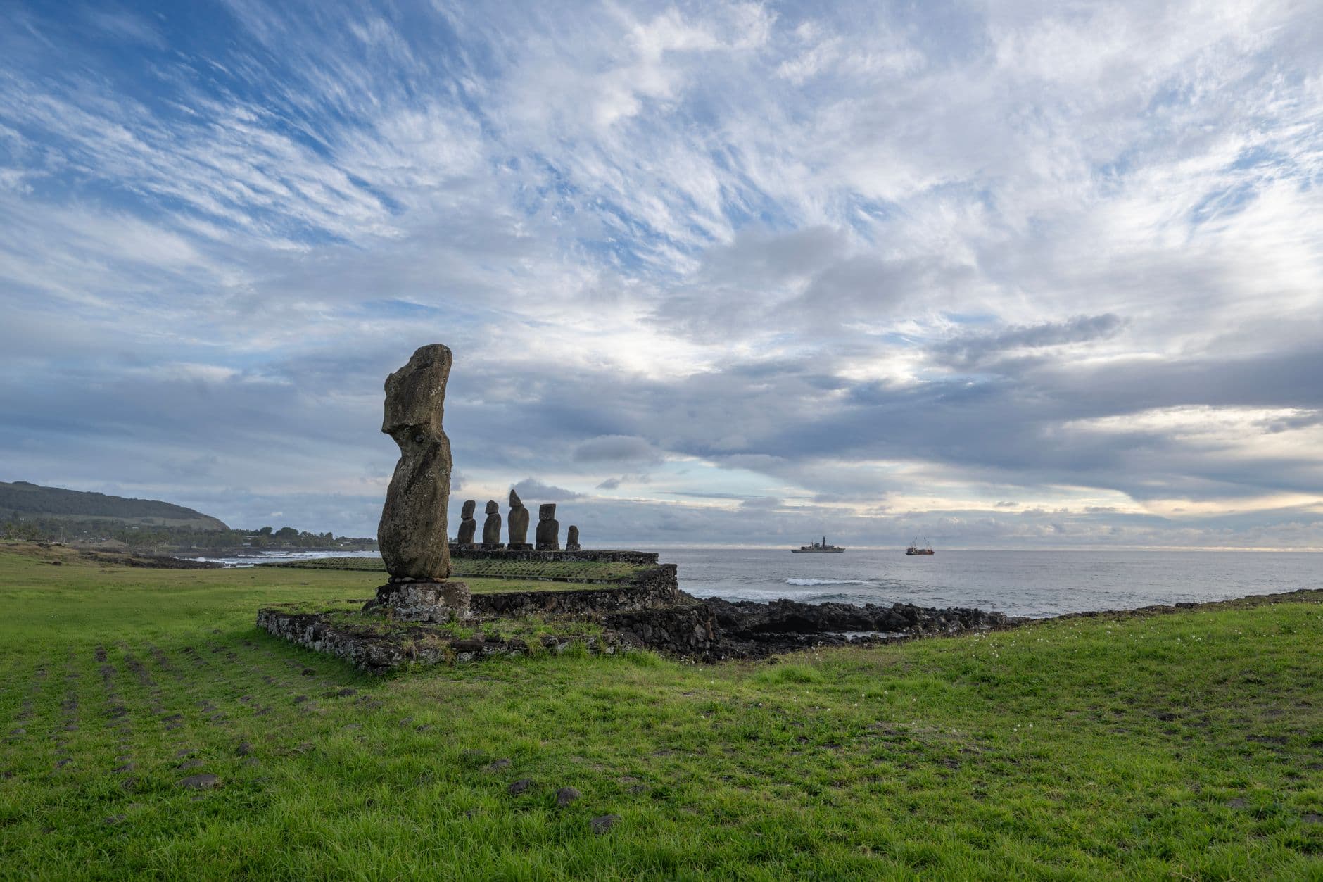 Scenic view of iconic Moai statues at Easter Island, Chile during a tranquil sunrise by the coast.