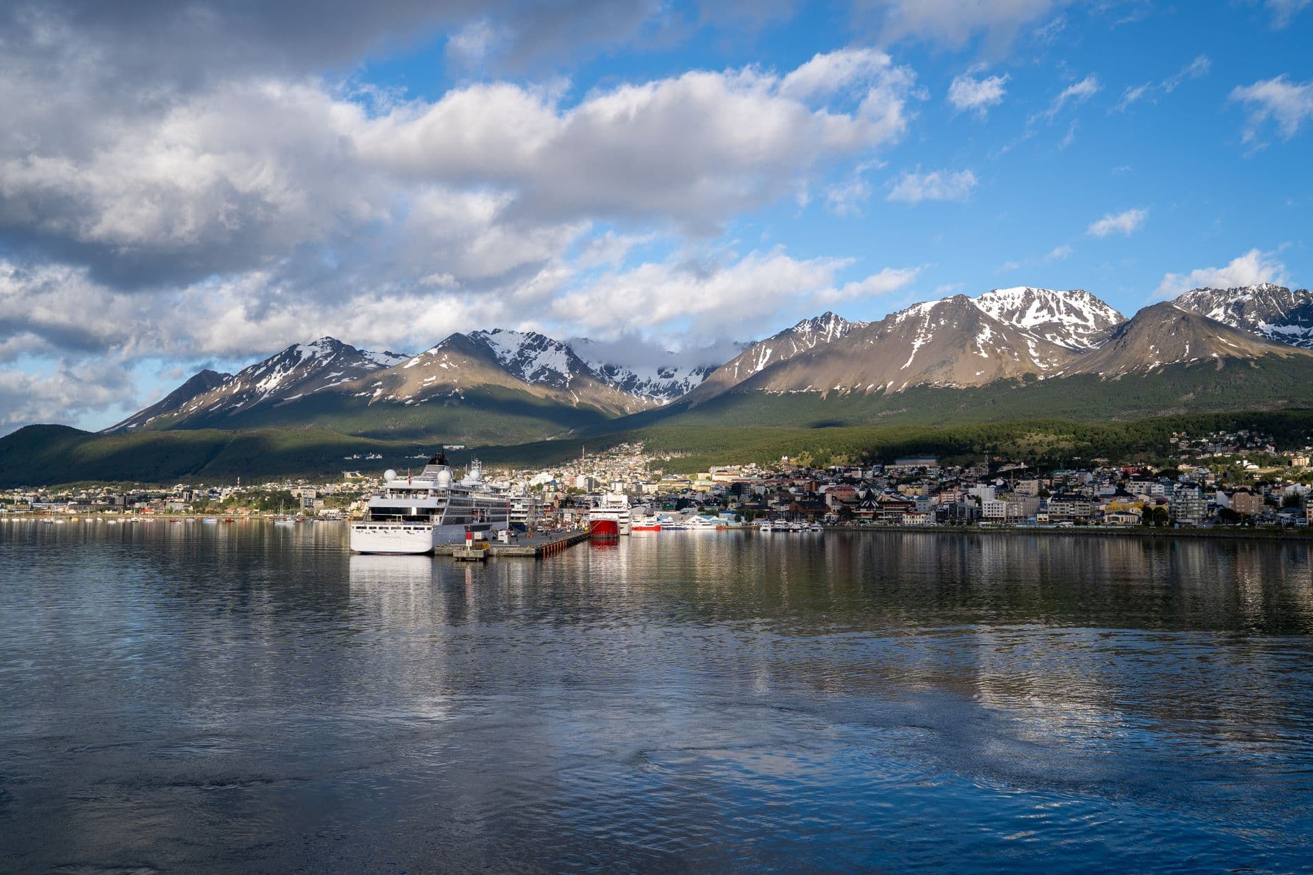 Captured in Ushuaia, this image shows a scenic harbor view backed by Andes Mountains.