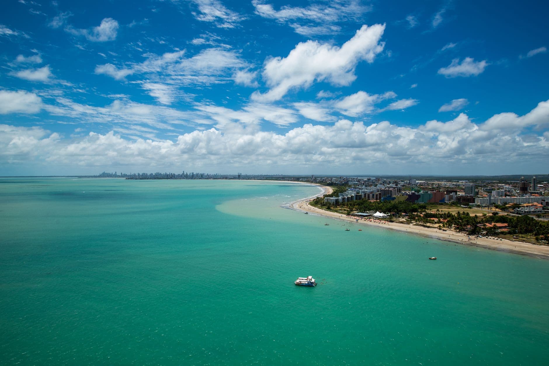 A breathtaking aerial view of João Pessoa's coastline, showcasing turquoise waters and vibrant summer skies.