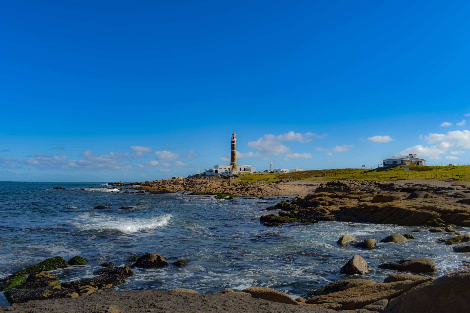 Scenic view of Cabo Polonio lighthouse with rocky coastline under a clear blue sky in Uruguay.