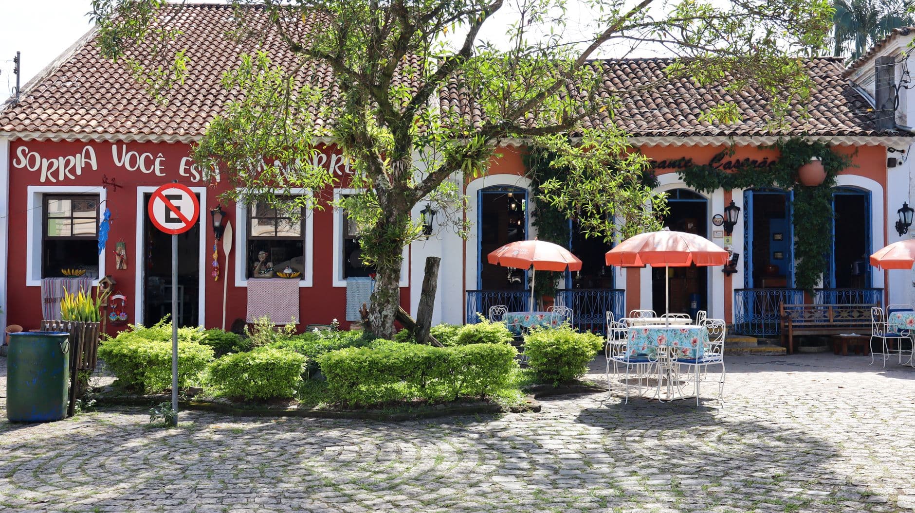 A quaint café with outdoor seating and vibrant umbrellas in a picturesque setting.