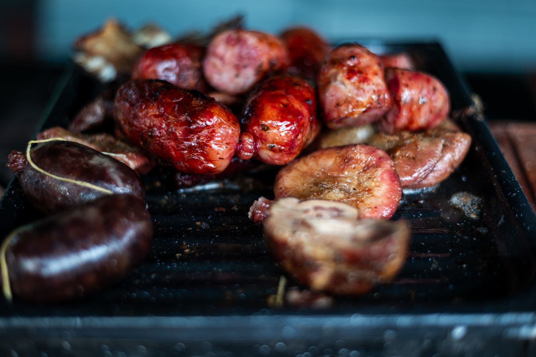 Close-up of traditional Argentine asado with chorizo and morcilla sizzling on a grill in Uribelarrea.
