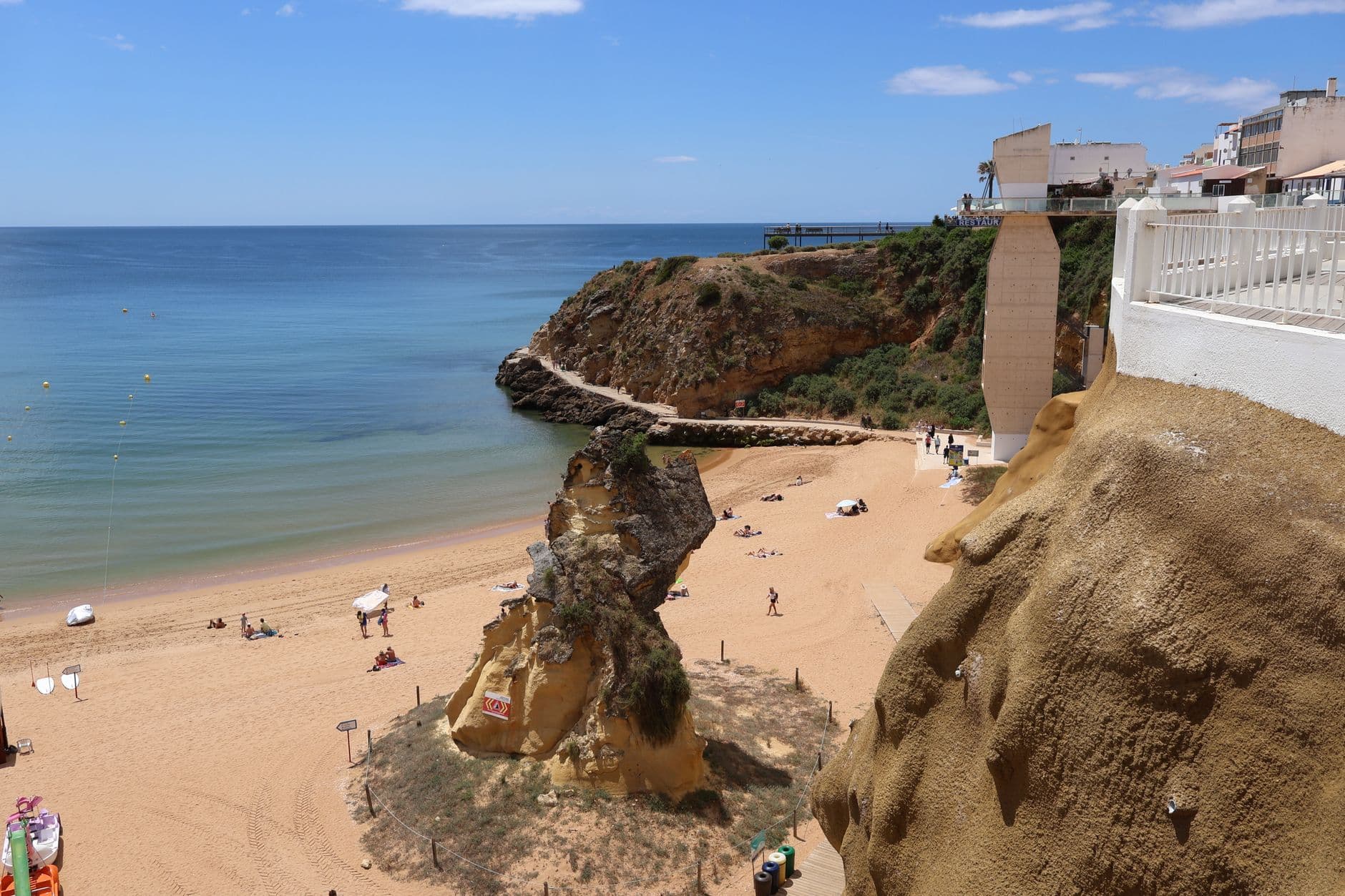 Beautiful beach with cliffs overlooking the calm sea under a clear blue sky.