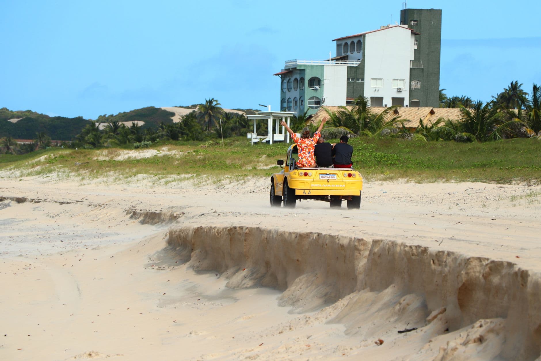 A yellow dune buggy on a beach with palm trees in scenic Rio Grande do Norte, Brazil.