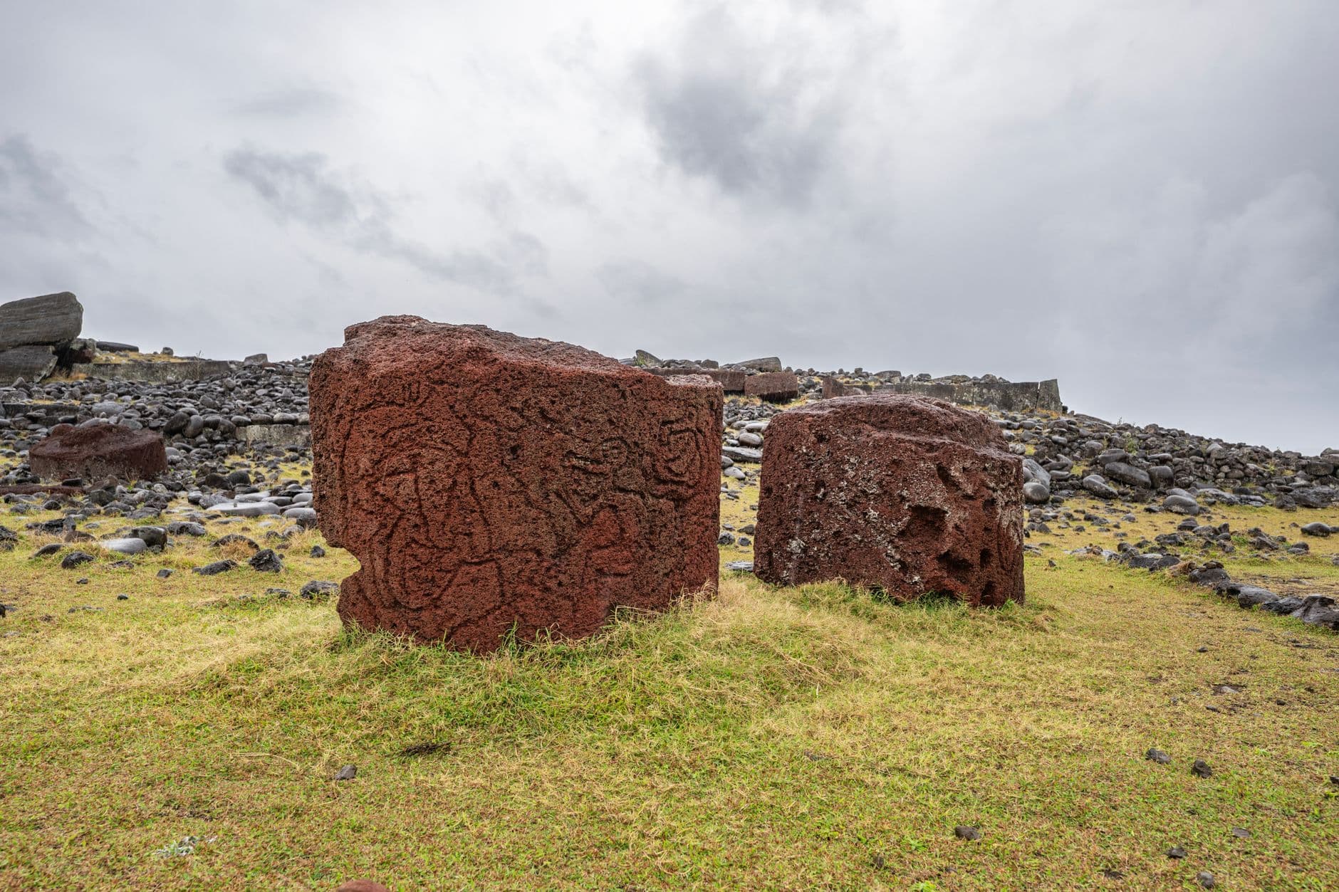 Two large volcanic stone blocks amidst a rocky landscape on Easter Island.