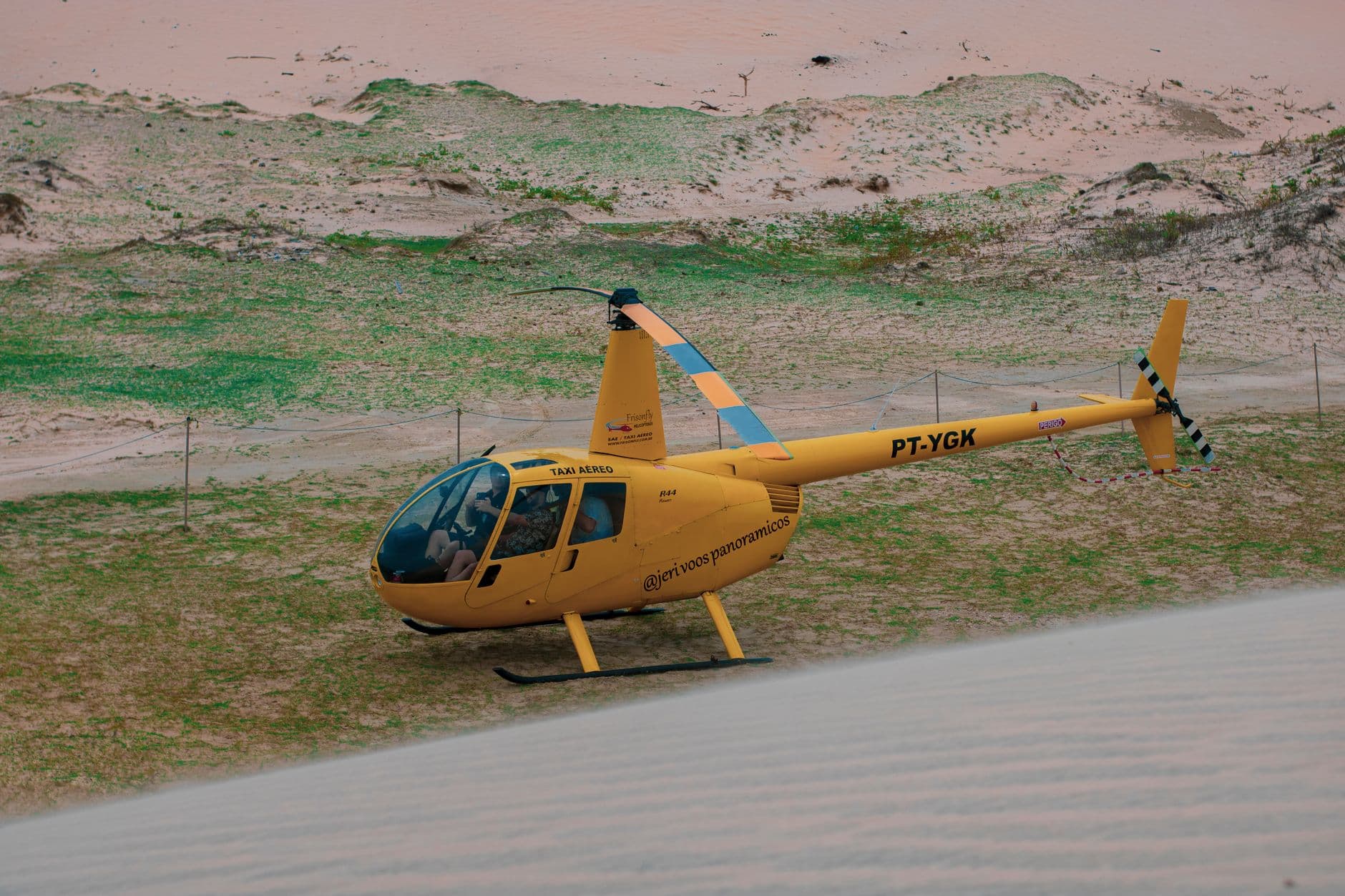 Yellow helicopter taxi on sand dunes in Jericoacoara, Brazil.