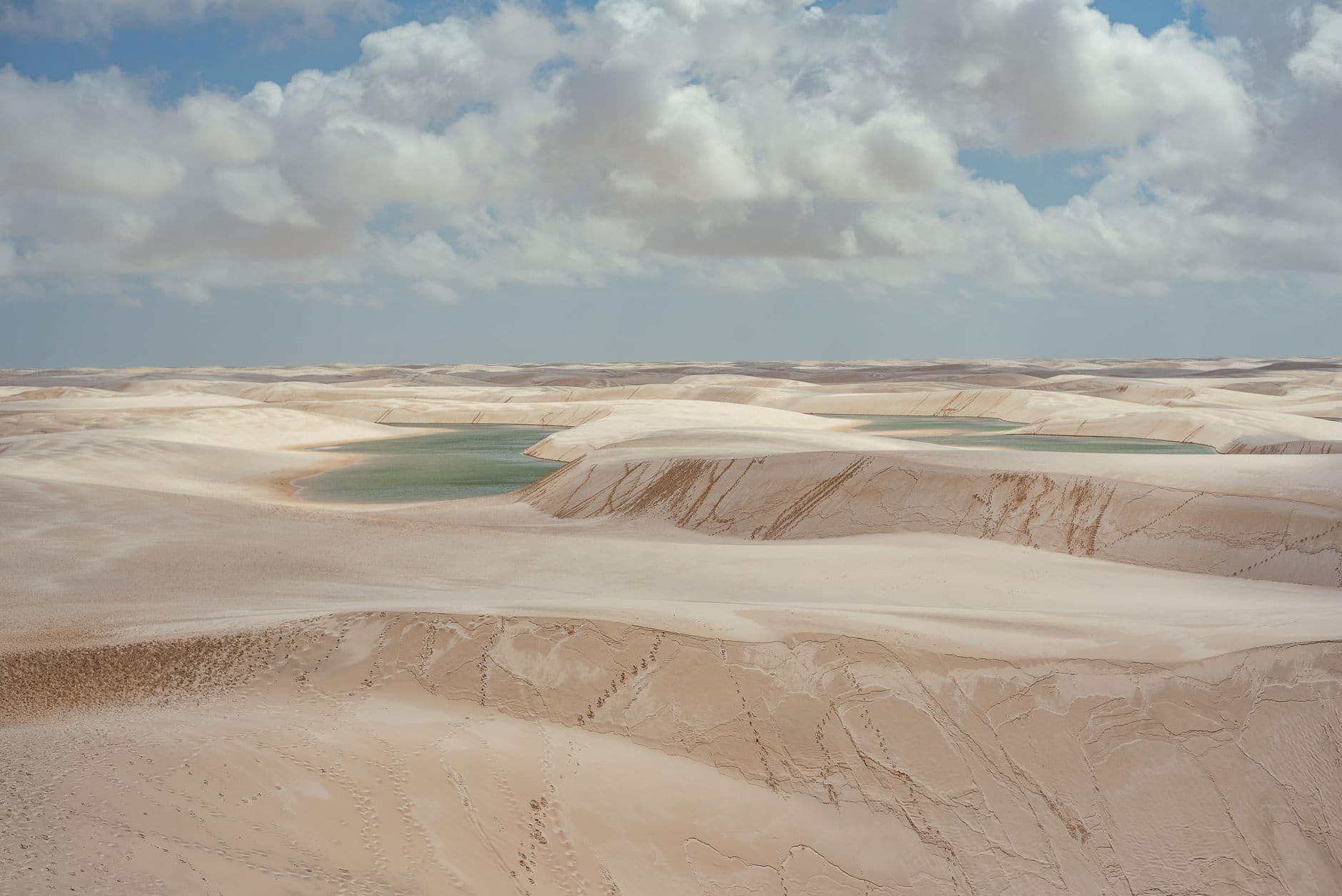 Beautiful aerial shot of Lençóis Maranhenses sand dunes in Brazil with picturesque lagoons and cloudy sky.