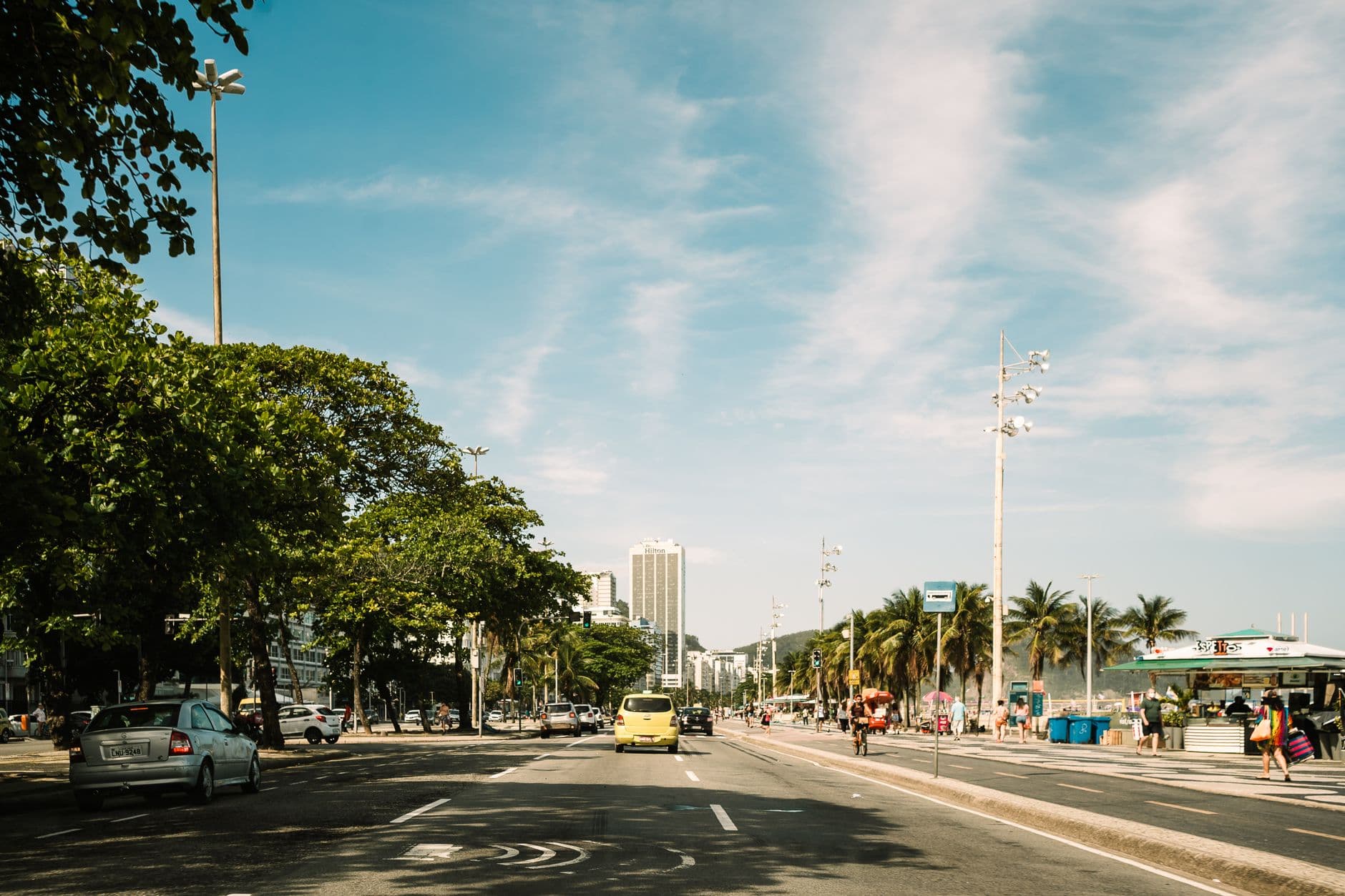 Vibrant daytime view of a bustling street with cars and people in Rio de Janeiro, Brazil.