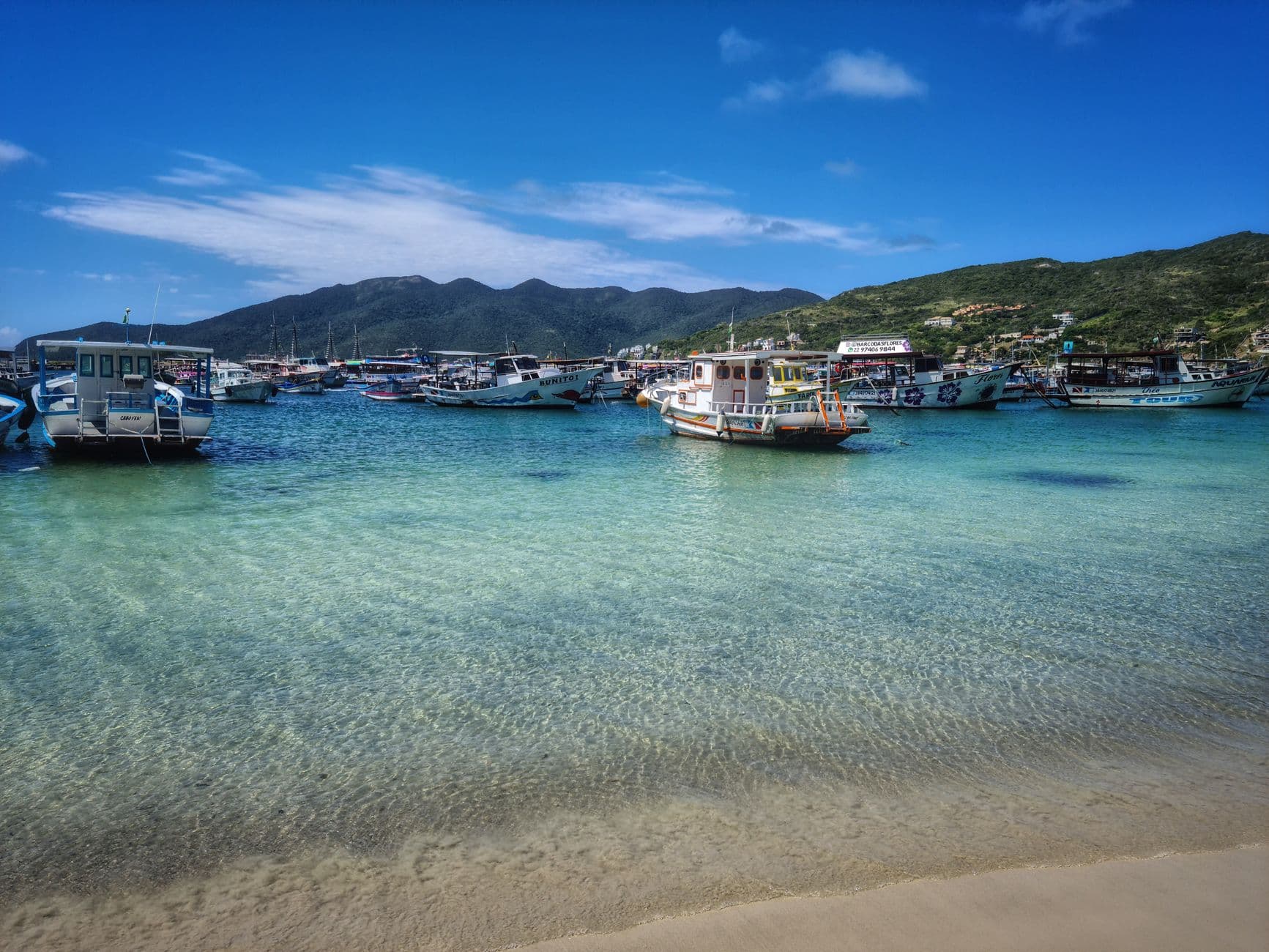 Boats floating on the turquoise waters of Arraial do Cabo, Brasil, under a bright blue sky.