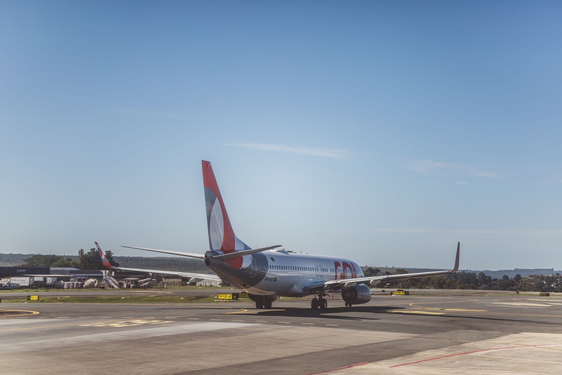 Airplane taxiing on the runway at an airport with a clear blue sky backdrop.