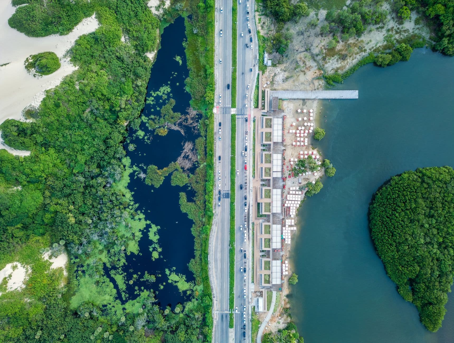 Drone shot capturing urban coastline, road, and greenery in Fortaleza, Brazil.
