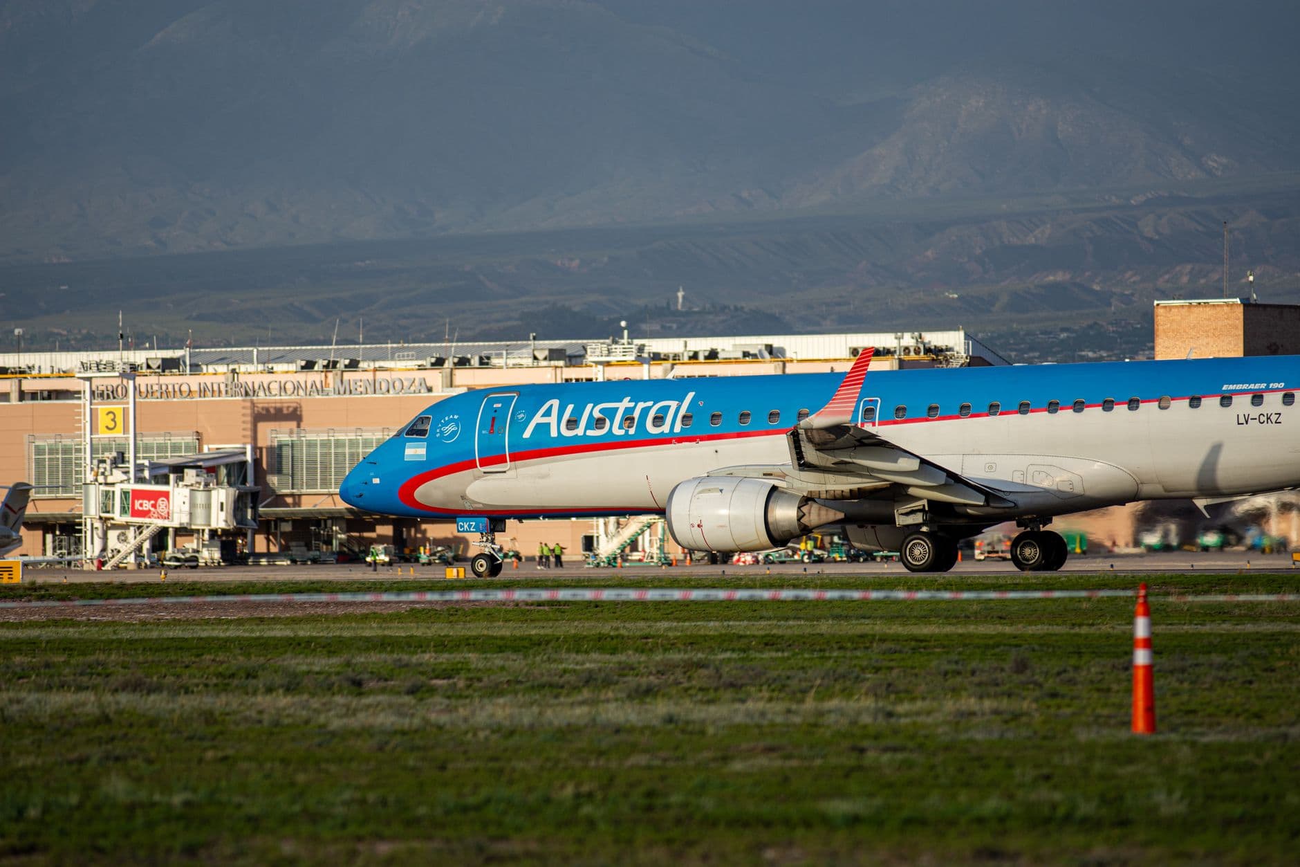 Austral Airlines Embraer aircraft on runway at Mendoza Airport with Andes backdrop.