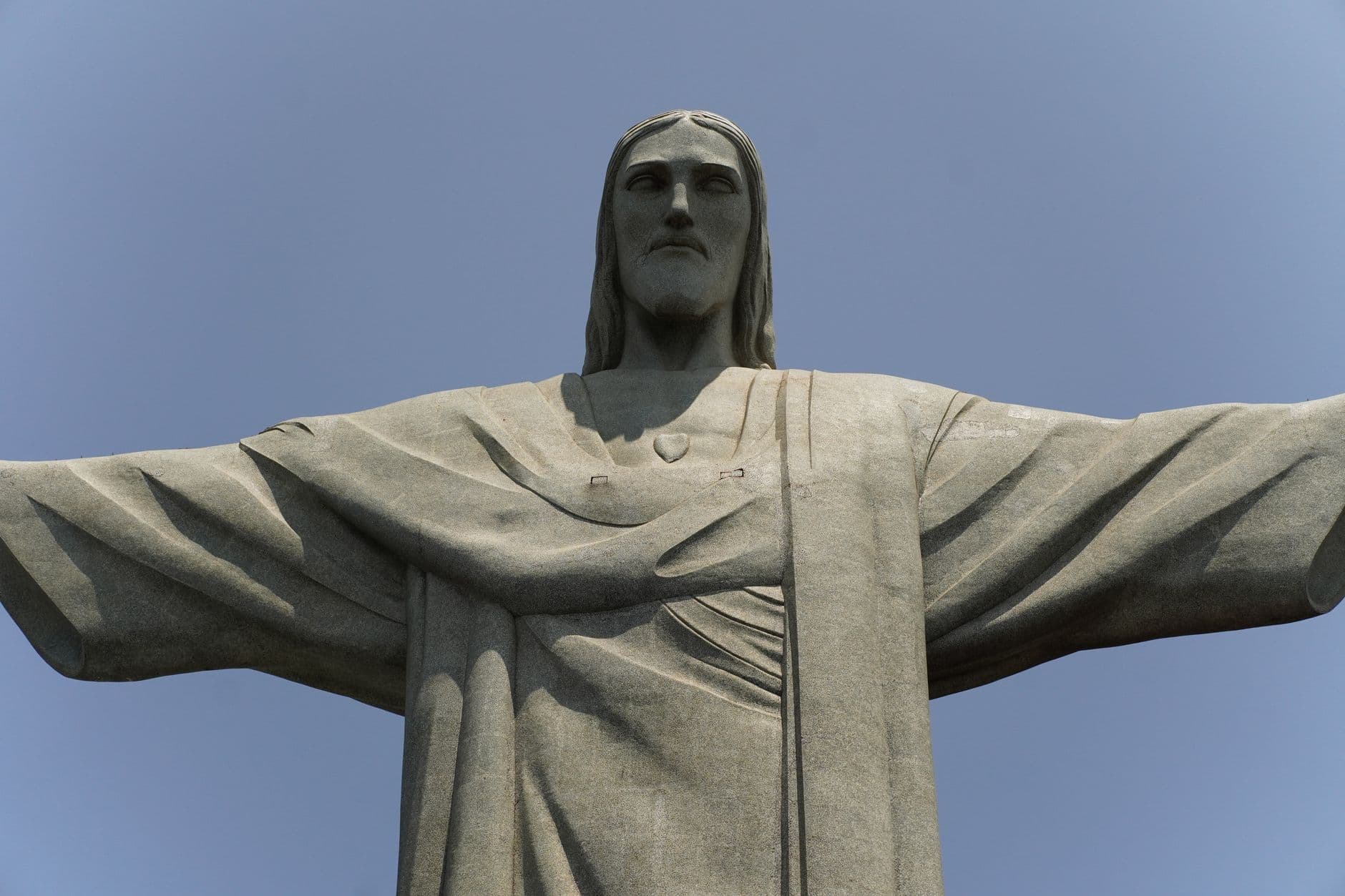 Up-close view of Christ the Redeemer statue against a clear blue sky in Rio de Janeiro.