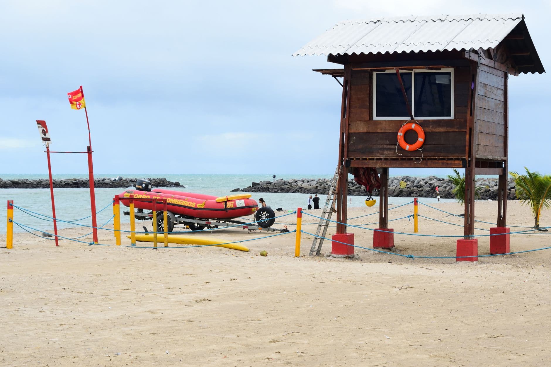 Wooden lifeguard station and boat on Olinda beach, Pernambuco, Brazil under a cloudy sky.