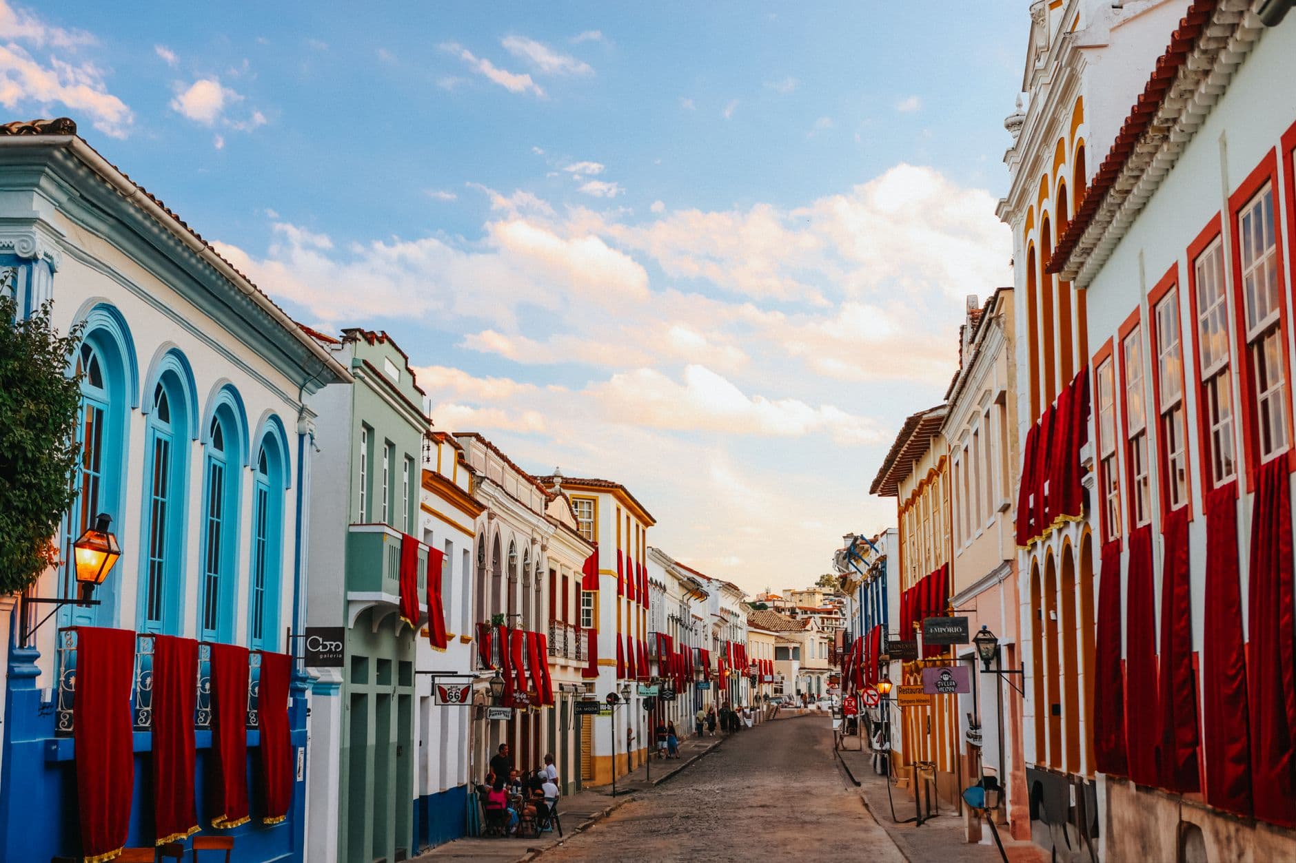 Vibrant colonial street with colorful facades and red decorations at sunset.