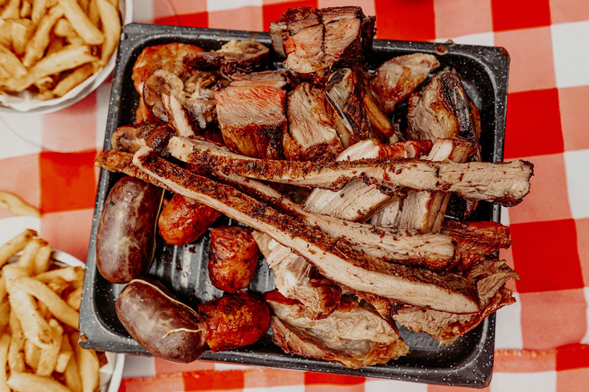 A mouth-watering Argentine asado platter featuring grilled meats on a traditional checkered tablecloth.