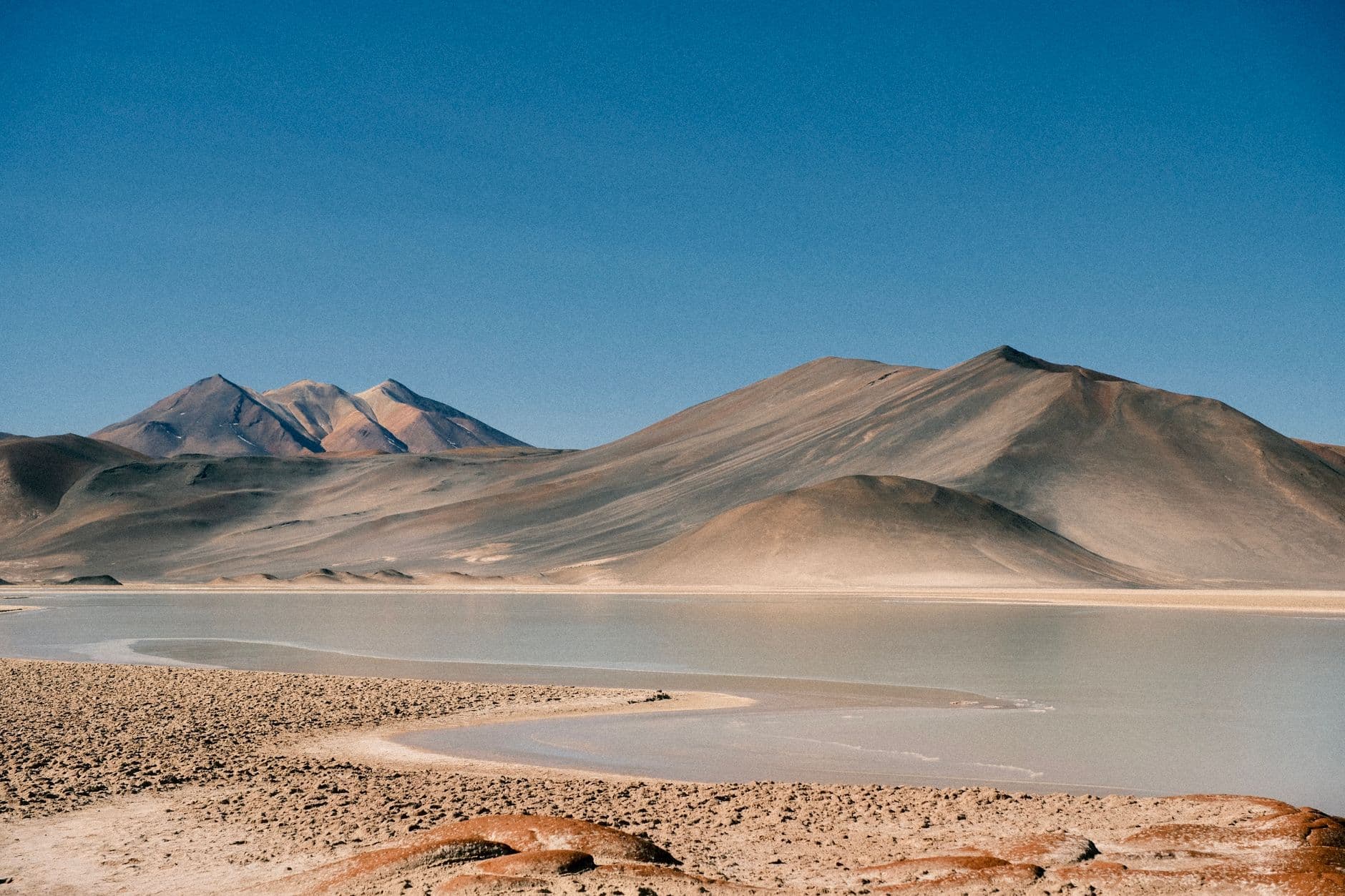 Explore the rugged beauty of the Antofagasta desert landscape with distant mountains under a clear blue sky.