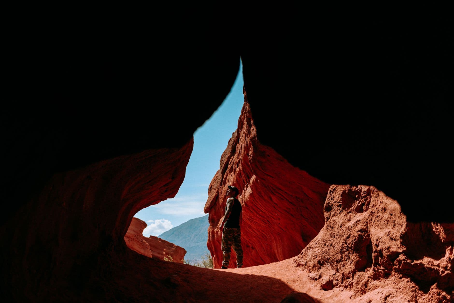 Explore the breathtaking red rock canyons of Cafayate, Argentina. An adventurer stands in awe.