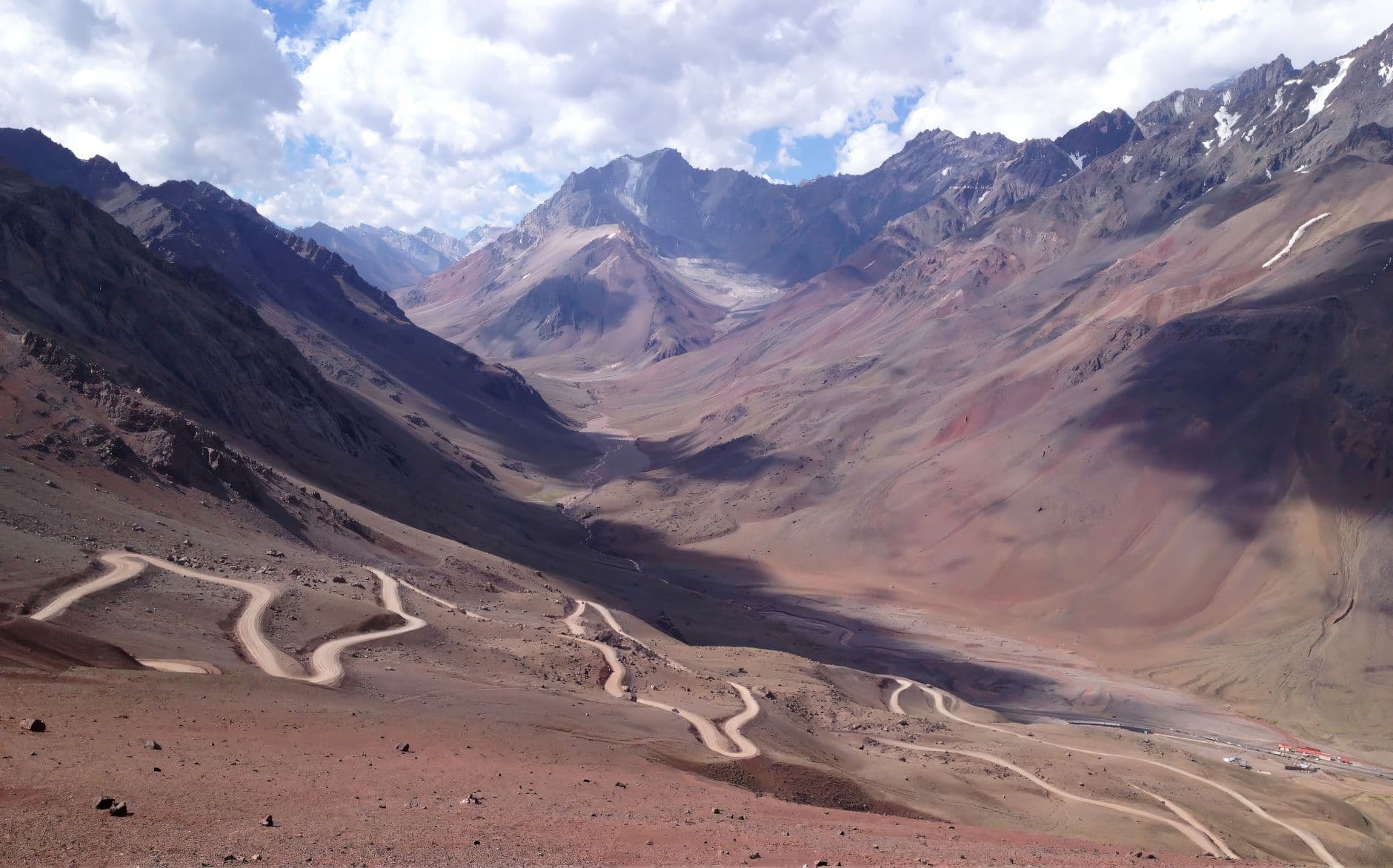 Breathtaking aerial view of the Andes Mountains in Mendoza, Argentina, featuring a winding road through a scenic valley.
