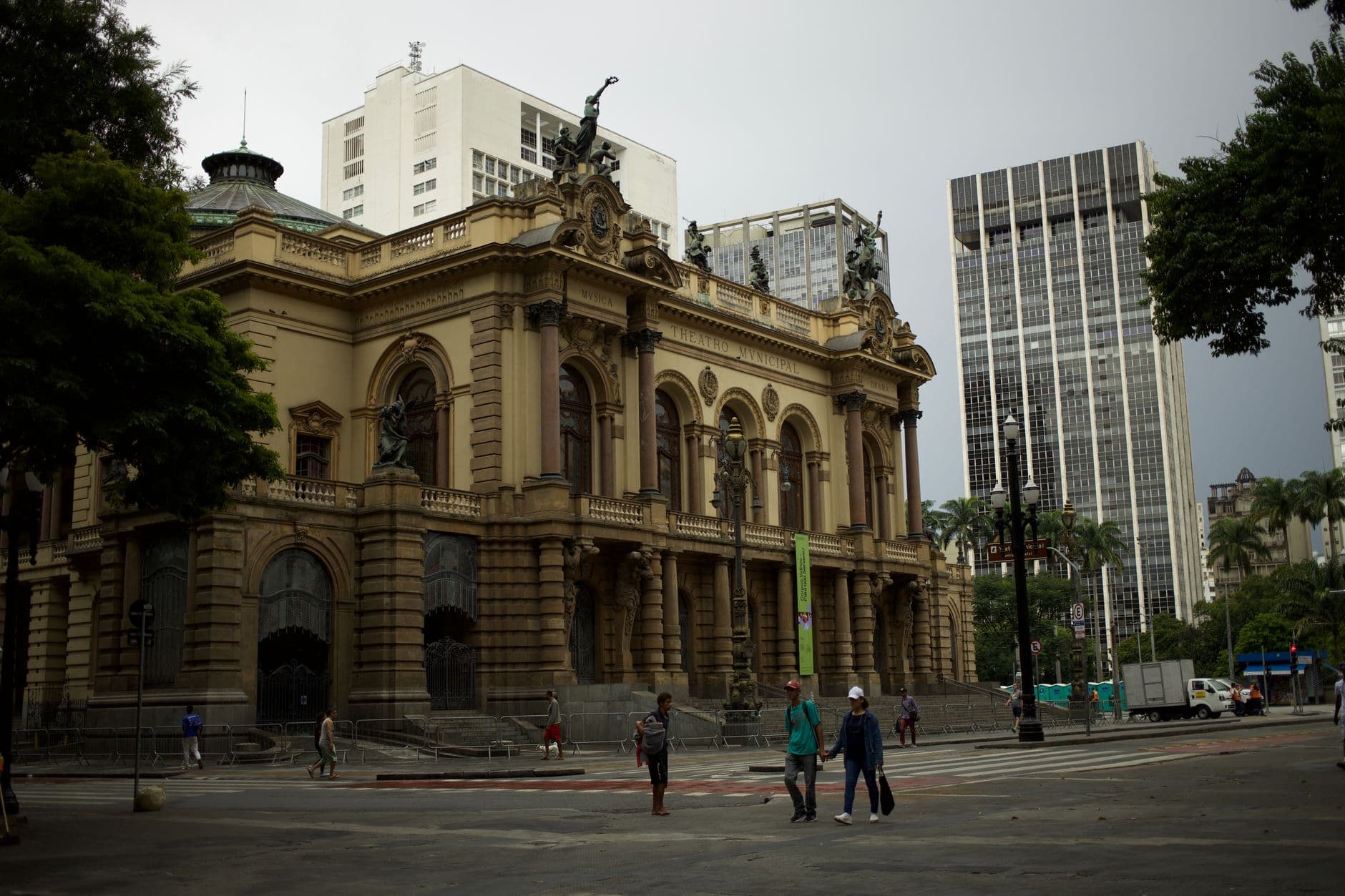 Urban scene featuring São Paulo's historic Municipal Theater with pedestrians passing by.