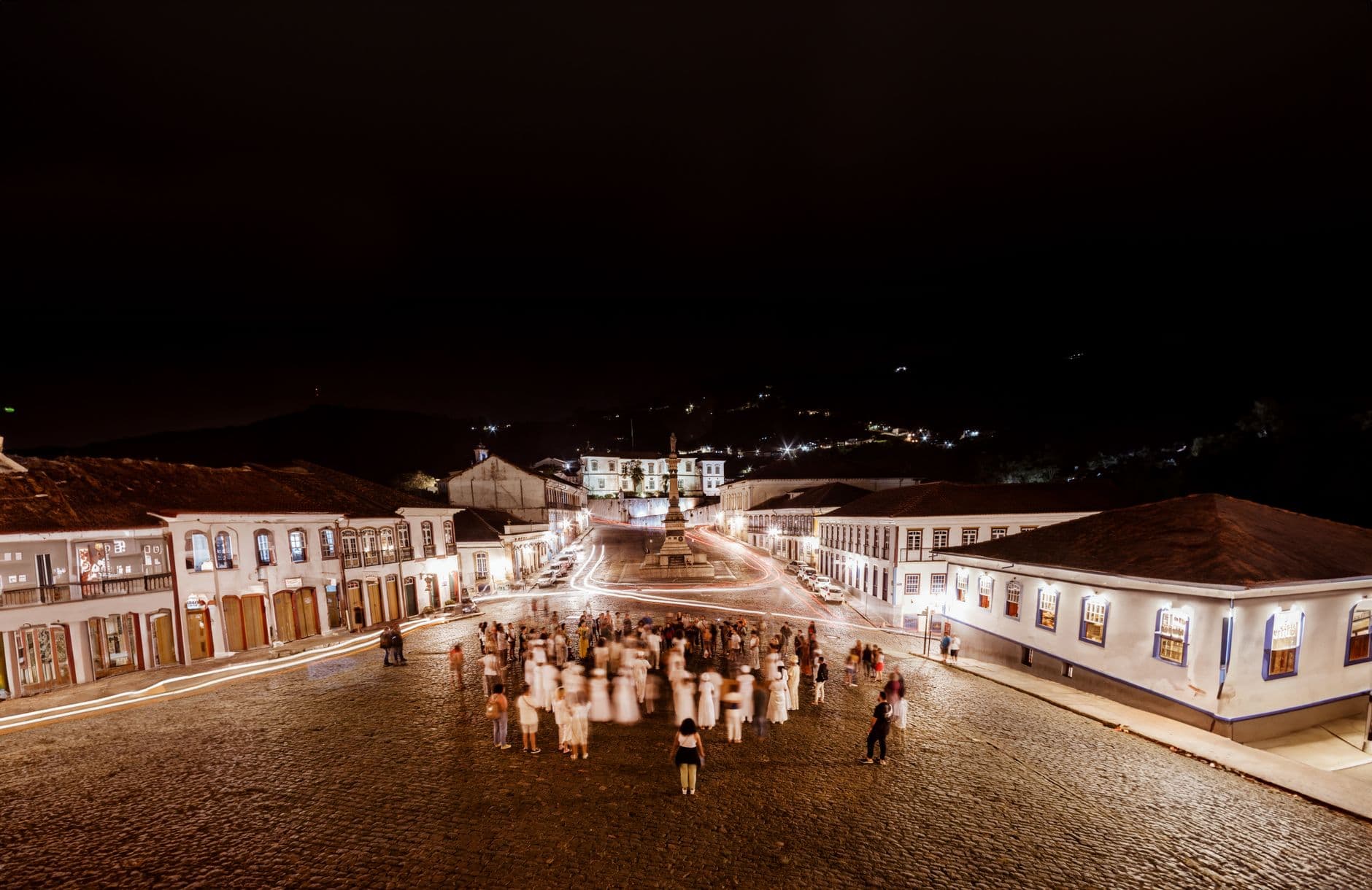 Captivating night shot of Ouro Preto town square, featuring illuminated colonial architecture and bustling crowd.