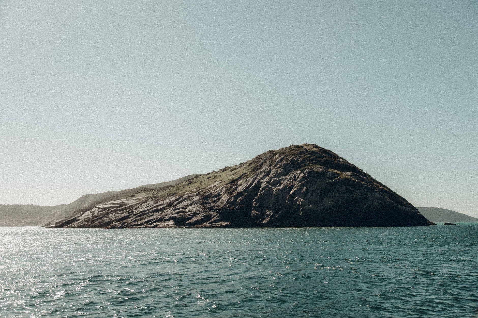 Breathtaking view of an island with rocky terrain surrounded by the sea in Arraial do Cabo, Brazil.