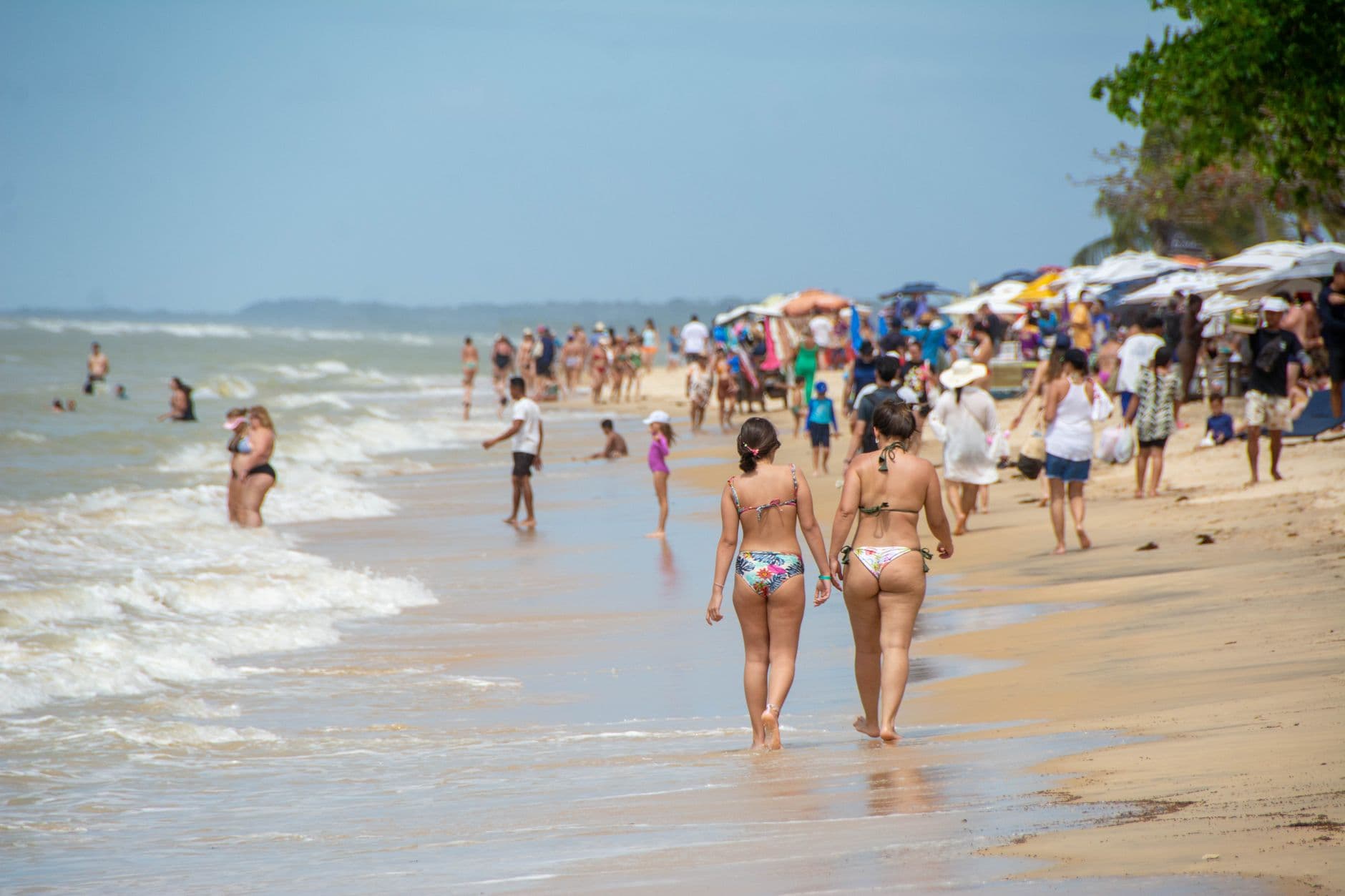 Crowded beach day in Porto Seguro, Brazil with people enjoying the summer sun and sea.
