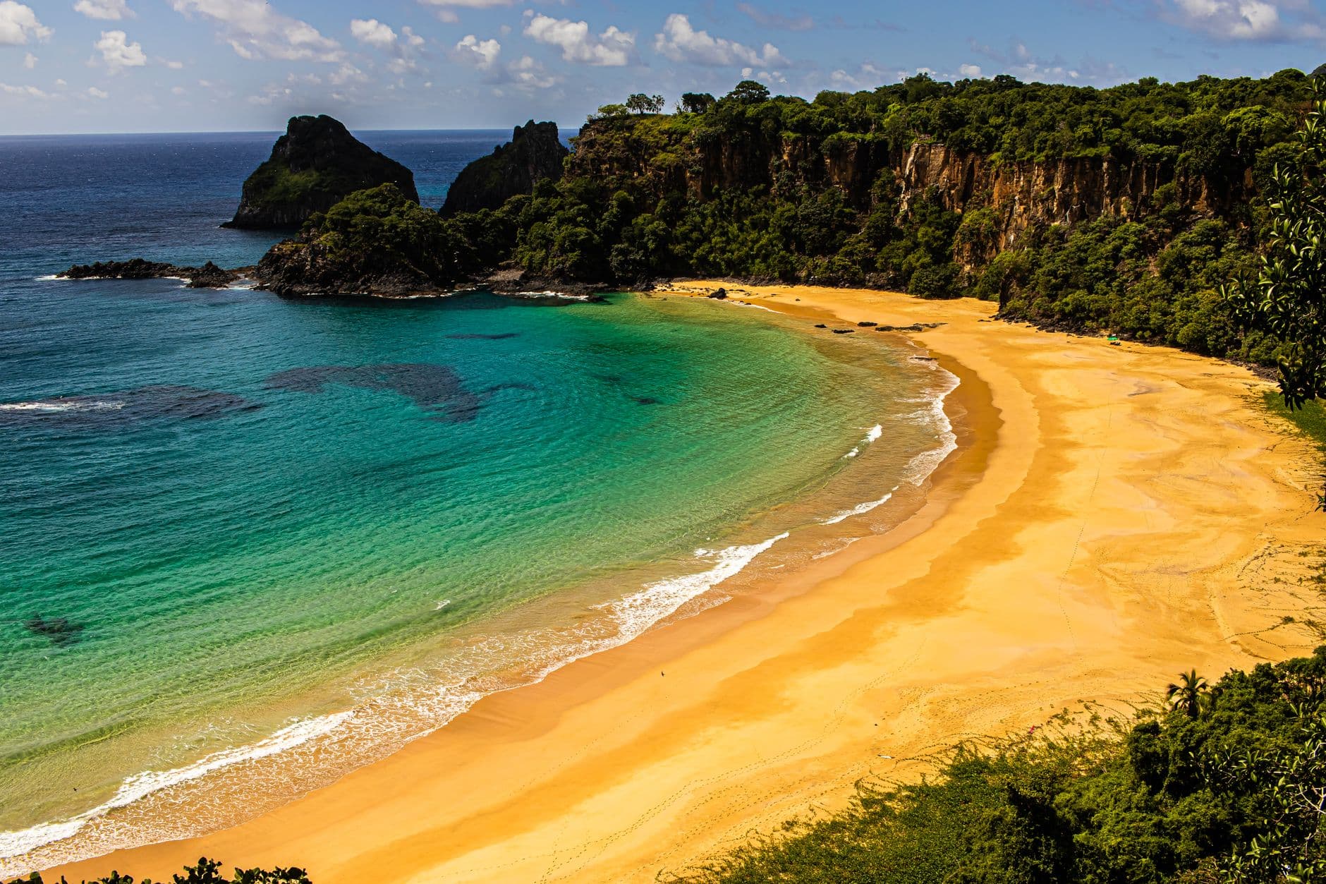 Beautiful aerial shot of Sancho Beach, showcasing turquoise water, golden sand, and lush cliffs in Brazil.