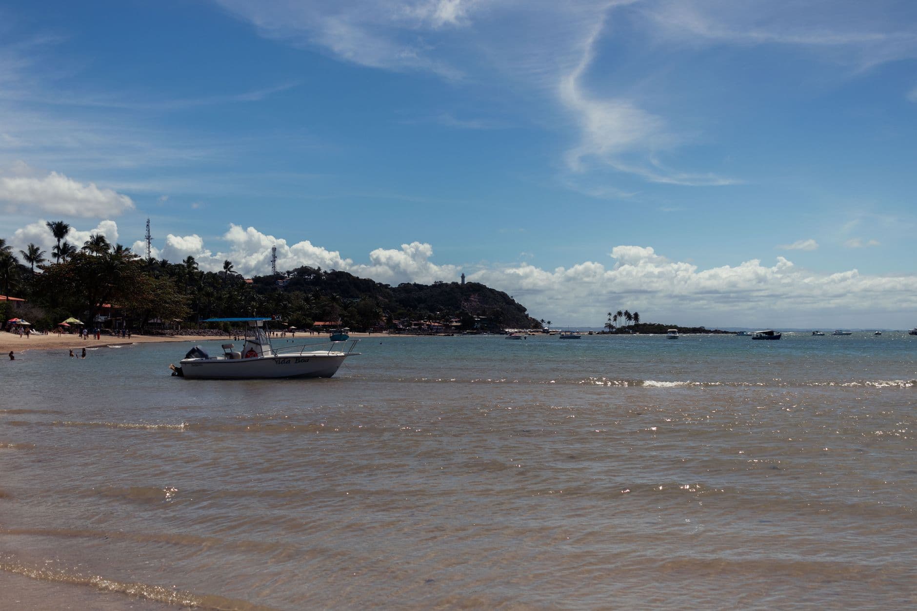 Picturesque view of a boat on the clear waters of Morro de São Paulo beach under a vibrant blue sky.