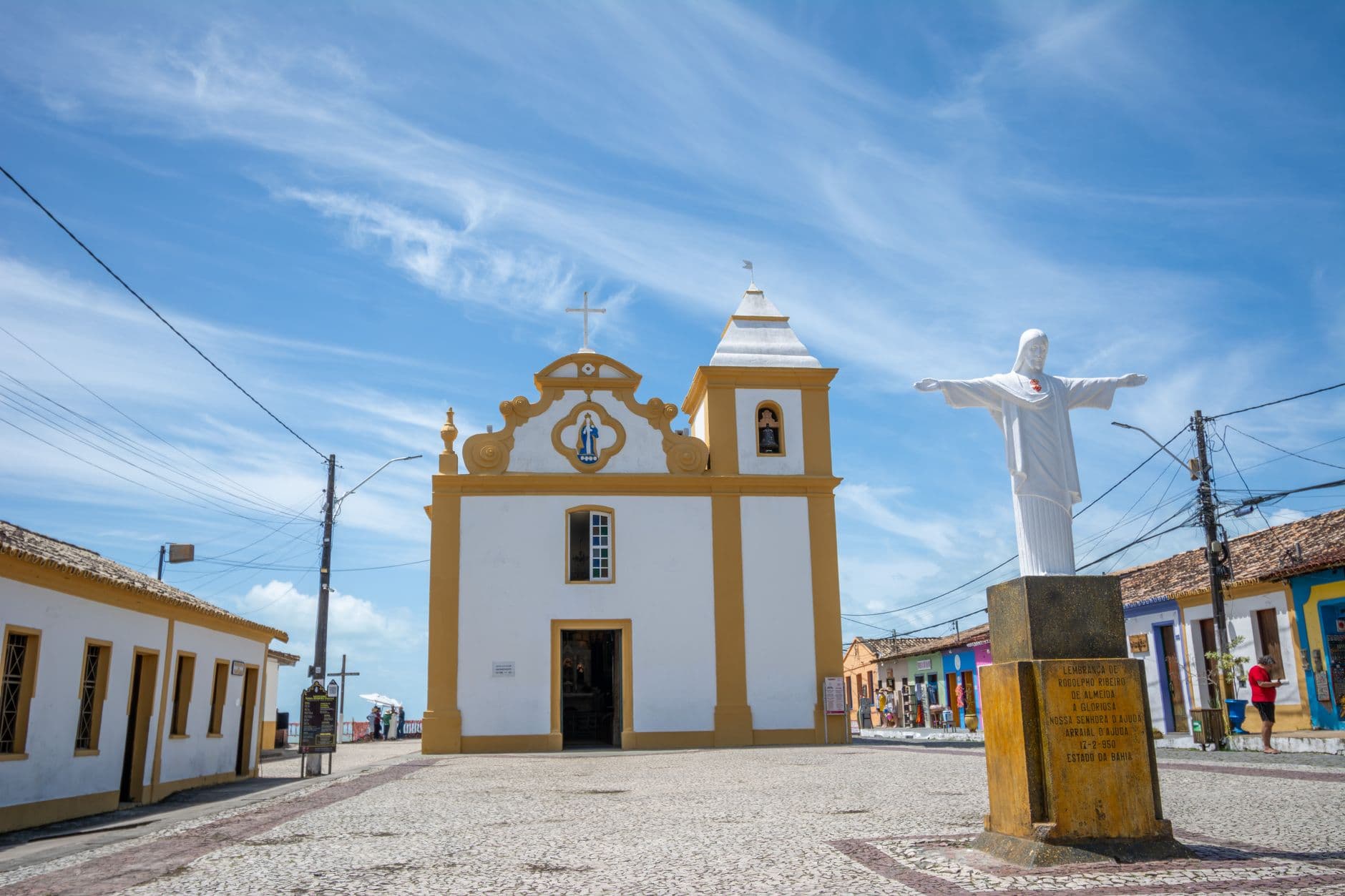 Historic church and Christ statue in Porto Seguro, showcasing colonial architecture.
